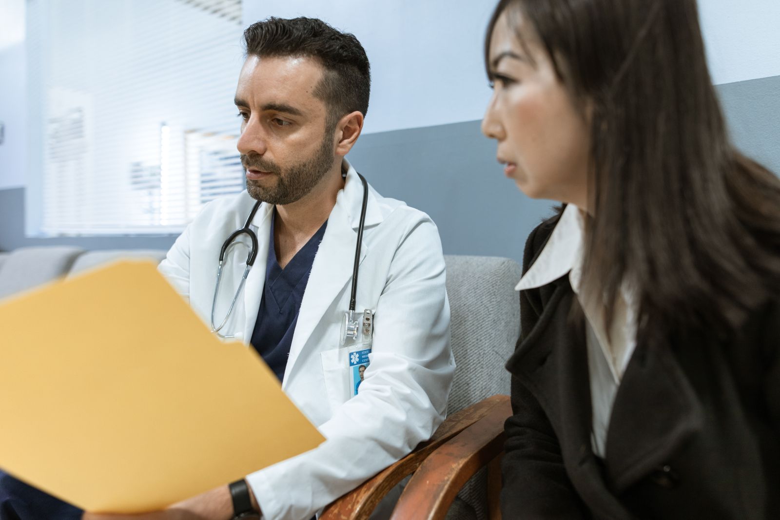 Un médico revisa una carpeta de antecedentes junto a una paciente
